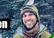 Smiling man with bird on his head.